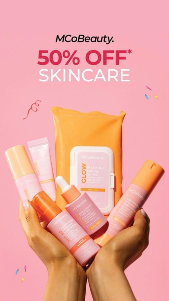 A bright, high-contrast promotional graphic showcasing a full range of beauty products held in hands against a solid pink background.